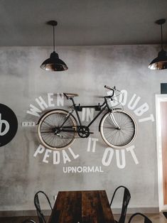 a bicycle mounted to the side of a wall next to tables and chairs in a restaurant