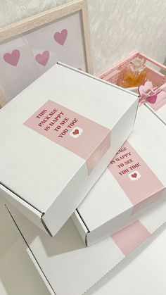 two boxes with pink hearts on them sitting on top of a white table next to each other