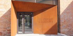 the entrance to an orange building with glass doors