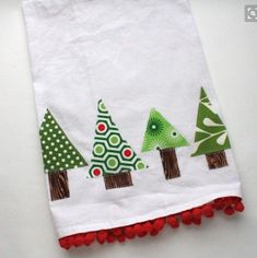 a white towel with christmas trees on it and pom poms around the edges