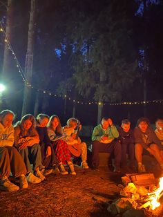 a group of people sitting around a campfire at night