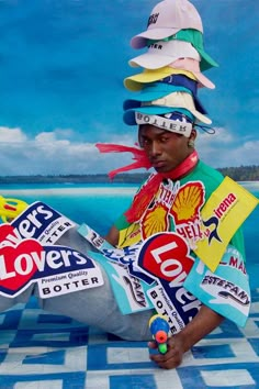 a man with lots of stickers on his head sitting in front of the ocean