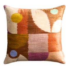 an orange and brown pillow with multicolored circles on the front, sitting on a white background