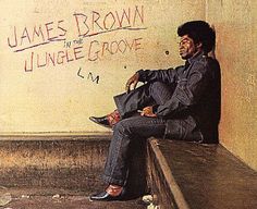 a man sitting on top of a wooden bench next to a wall covered in graffiti