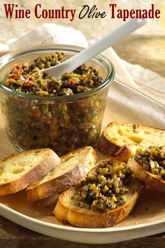 a plate topped with bread and some type of concoction next to a jar of wine