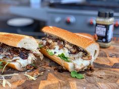 two sandwiches cut in half sitting on top of a cutting board next to a jar of mustard