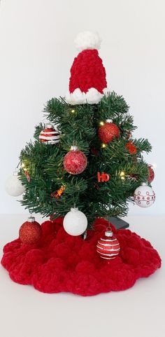 a knitted christmas tree with red and white ornaments on the top, in front of a white background