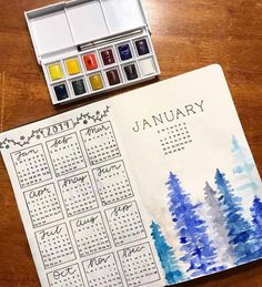 a calendar with watercolors on it sitting next to a paintbrush