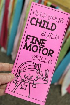 a hand holding up a pink book with writing on it that says help your child build fine motor skills