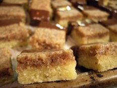 several pieces of cake sitting on top of a wooden cutting board with chocolate in the background