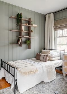 a bed sitting in a bedroom next to a window with bookshelves on the wall