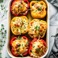 baked stuffed bell peppers in a casserole dish with cheese and herbs on top