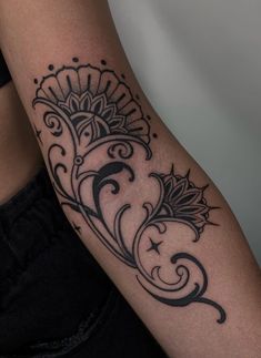 a woman's arm with a black and white tattoo design on the left shoulder