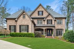 a large brick house with lots of windows and green grass in front of the house