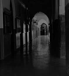 an empty hallway leading to two doors and a clock hanging on the wall in black and white