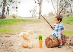 a little boy that is sitting on a log with a teddy bear next to it