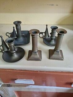 several metal vases are sitting on top of a table next to an oven door