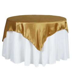 a gold and white table cloth on top of a round table with a satin overlay