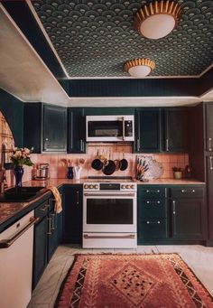 a kitchen with green cabinets and an area rug in front of the stove top oven