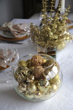 a glass bowl filled with ornaments sitting on top of a white tablecloth covered table