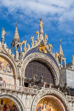 an ornate building with statues and paintings on the front wall, against a blue sky