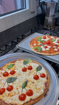 two pizzas sitting on top of pans covered in cheese and tomato toppings