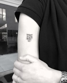 a black and white photo of a woman's arm with a small tiger tattoo on it