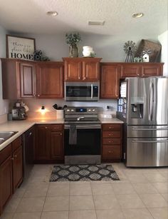 a kitchen with wooden cabinets and stainless steel appliances in the center, along with an area rug on the floor