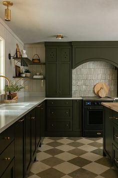 a kitchen with green cabinets and checkered flooring on the floor, along with an oven