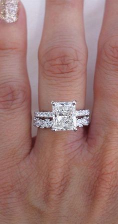 a woman's hand with two wedding rings on it and an engagement ring in the middle