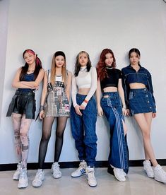 four girls are standing in front of a wall