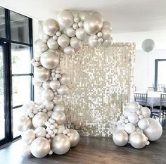 balloons are arranged in the shape of an arch with white and silver balls hanging from it