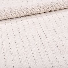 a white crocheted blanket laying on top of a bed next to a pillow