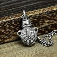 a silver pendant with an octopus on it's face is sitting on a wooden surface