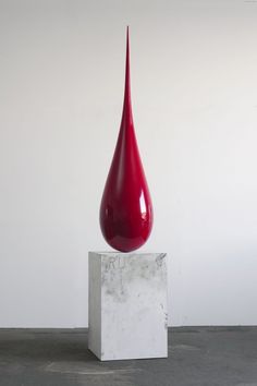 a red vase sitting on top of a white block