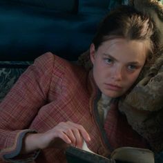 a woman laying on top of a couch reading a book