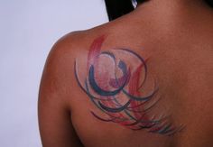 the back of a woman's shoulder with colorful tattoos on her upper arm and chest