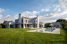 a large white house sitting on top of a lush green field next to a swimming pool