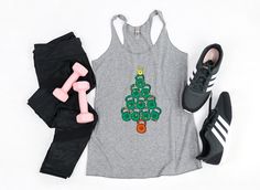 This kettlebell Christmas tree women's tank top is the perfect top for your next HIIT workout, yoga session, Crossfit, or gym class.  This top will get lots of laughs and compliments from your gym buddies during the holiday season!  This cute kettlebell Christmas tree tank top is so cool and comfortable, it also makes for great casual or lounge wear.   MUSCLE TANK Garment Features:  * Great for pairing with Bralettes and Sports Bras * Low Arm Hole * Relaxed Fit * Lightweight & Thin Fit & Sizing: * Please see sizing chart Materials: * 65% poly, 35% viscoe * Fabric weight: 3.7 oz Quality & Care: * Printed and designed in the USA * Machine wash cold, inside out, and tumble dry RACERBACK TANK Garment Features:  * Sideseemed * Women's cut * Raw edge design * Racerback * Lightweight & Thin Fit & Gym Buddies, Crossfit Weightlifting, Weightlifting Gym, Holiday Workout, Fitness Gift, Gym Buddy, Gym Shirt, Workout Tank Top, Fitness Gifts