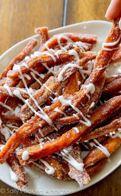 someone is dipping some kind of sweet potato fries with white icing on top and drizzled