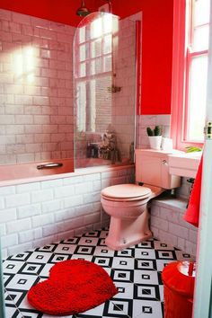 a white toilet sitting next to a pink bath tub in a bathroom under a window