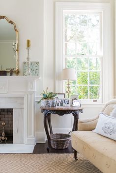 a living room filled with furniture and a fire place in front of a mirror on the wall