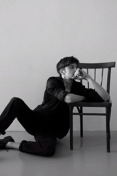 a young man sitting on the floor next to a chair eating an ice cream cone