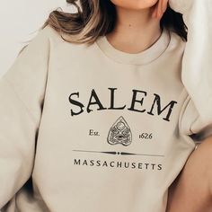 🩴 Salem Massachusetts Established 1626 Ouija Planchette Sweatshirt. Perfect witchy shirt for book lover or reader of historical literature.  Buy now for Halloween.  🩴 Click here to view our shop for more great designs --- https://www.etsy.com/shop/GraceAndFlipFlops Click on the ❤️ to see our new designs as they arrive. 🩴 Gilden Brand Sweatshirt - This unisex heavy blend crewneck sweatshirt is pure comfort. These garments are made from polyester and cotton. This combination helps designs come Salem Massachusetts Sweatshirt, Massachusetts Fall, Salem Witches, Fall Crewneck Sweatshirt, Witchy Shirt, Fall Crewneck, Witch Sweatshirt, Salem Massachusetts, Party Sweaters