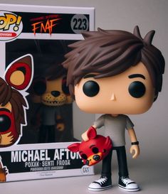 a pop vinyl figure holding a red fox in front of a box with an image of michael affuk on it