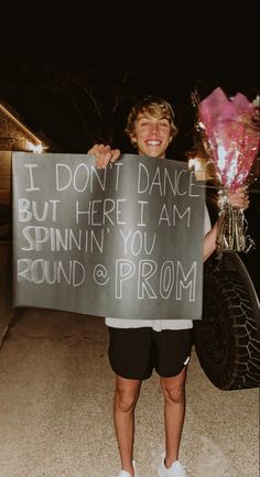 a boy holding a sign that says i don't dance but here i am spinin you round and prom