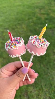 two pink cake pops with sprinkles and candles