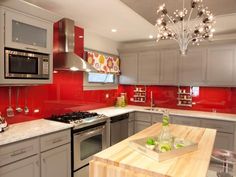 a kitchen with grey cabinets and red backsplash