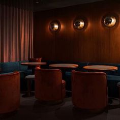 a dimly lit room with blue velvet seating and round lights on the wall behind it