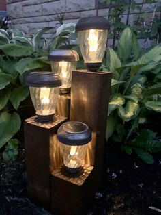 three lights that are on top of some wooden blocks in the grass and plants behind them